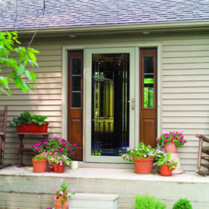 Front entrance with a glass storm door framed by wooden side panels and surrounded by potted plants