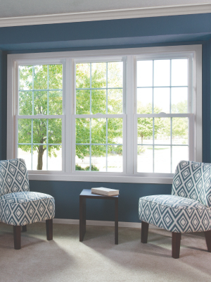 a blue wall with white windows with patterned chairs in front