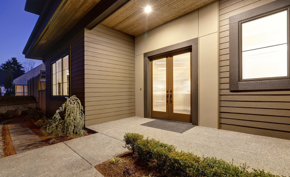 A contemporary home entrance with double glass doors lit by warm lighting